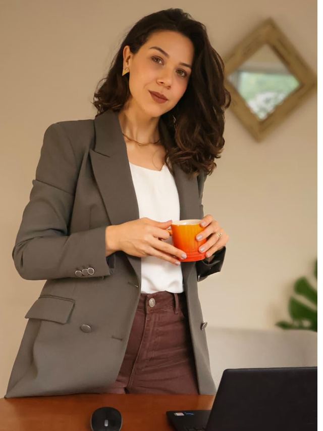 Ana Maria Moura com uma xícara de café, ao lado da mesa de atendimento